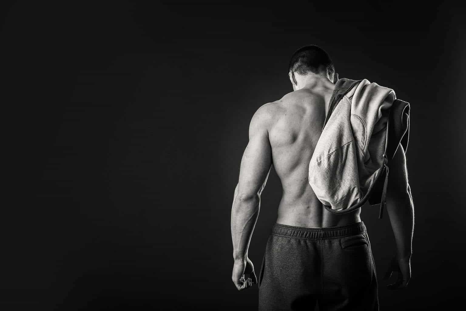 Healthy muscular young man after a workout on dark background.