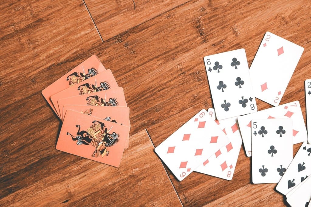 Speelkaarten liggen verspreid op een houten tafel tijdens een ontspannen kaartspel met vrienden.