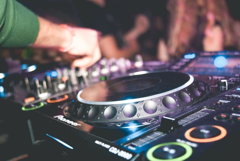 DJ bedient een mixer en draait muziek tijdens een levendig feest in een club.