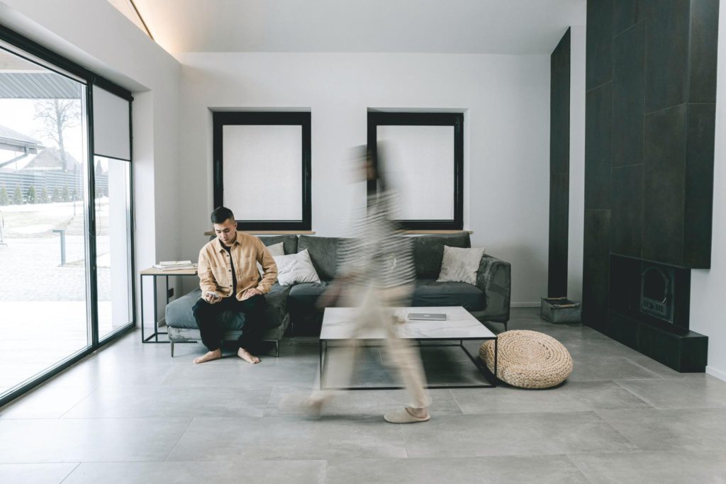 Minimalistisch interieur met persoon op de bank terwijl iemand in beweging door de ruimte loopt